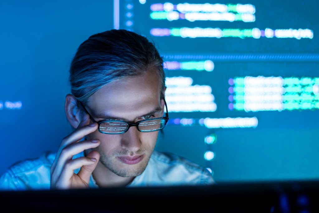 man wearing glasses looking at his computer screen